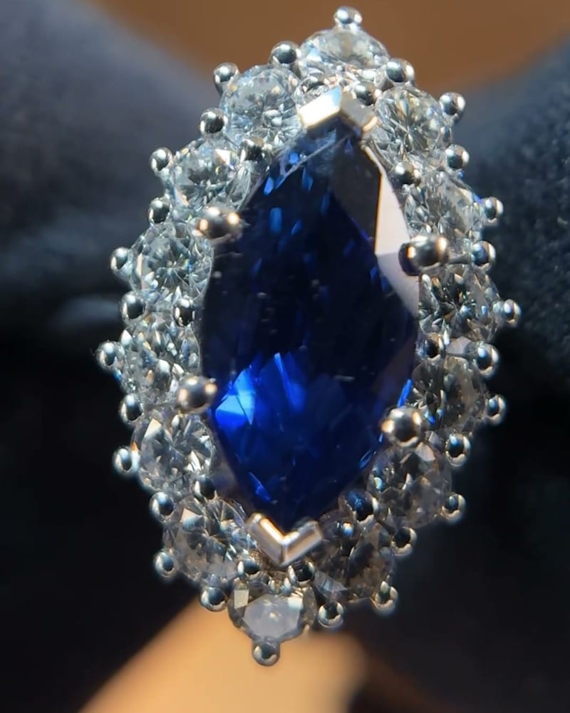 Marquise sapphire and diamond ring resting on the edge of a wooden surface