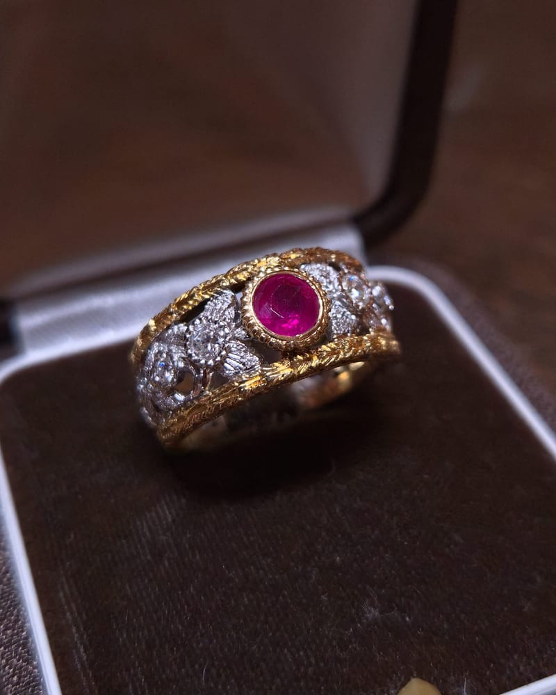 Wide openwork band in yellow and white gold with a ruby at the centre, in a velvet box